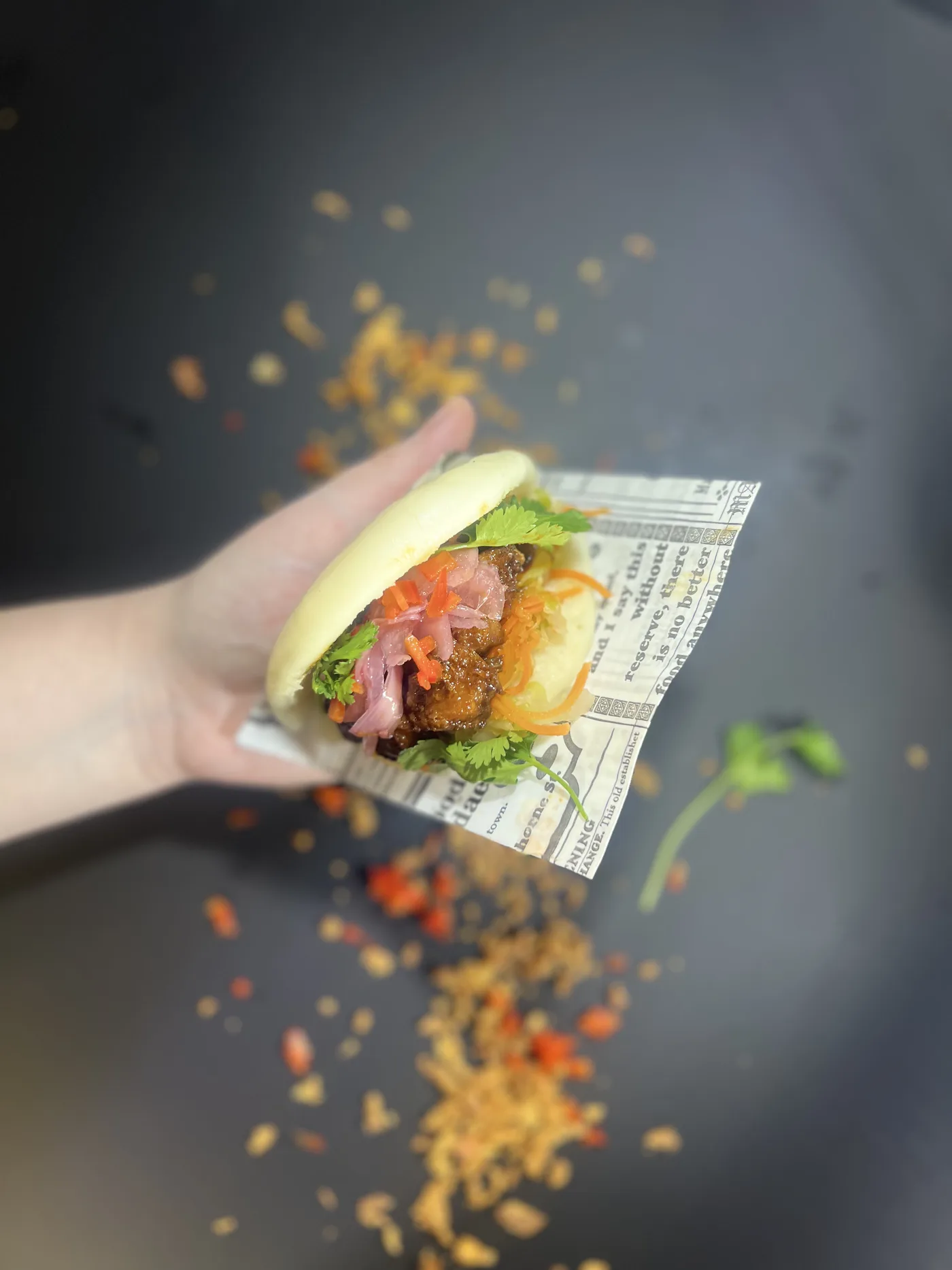 Kädessä pidetty bao-sämpylä, kasviksia ja yrttejä